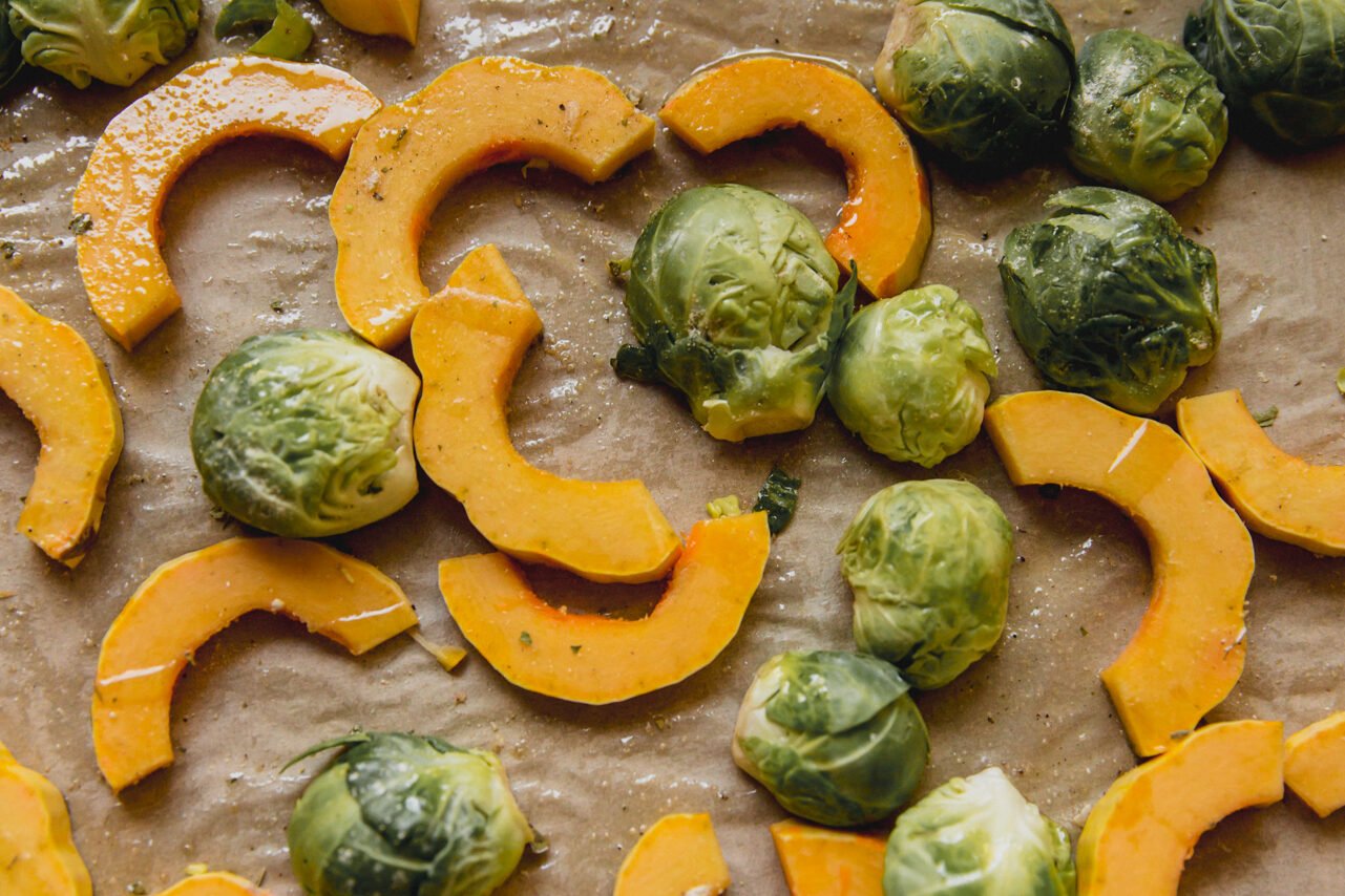 The brussels sprouts and squash on the baking sheet before roasting.