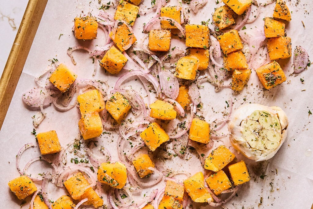 The butternut squash, garlic, and shallot on a baking sheet to roast.