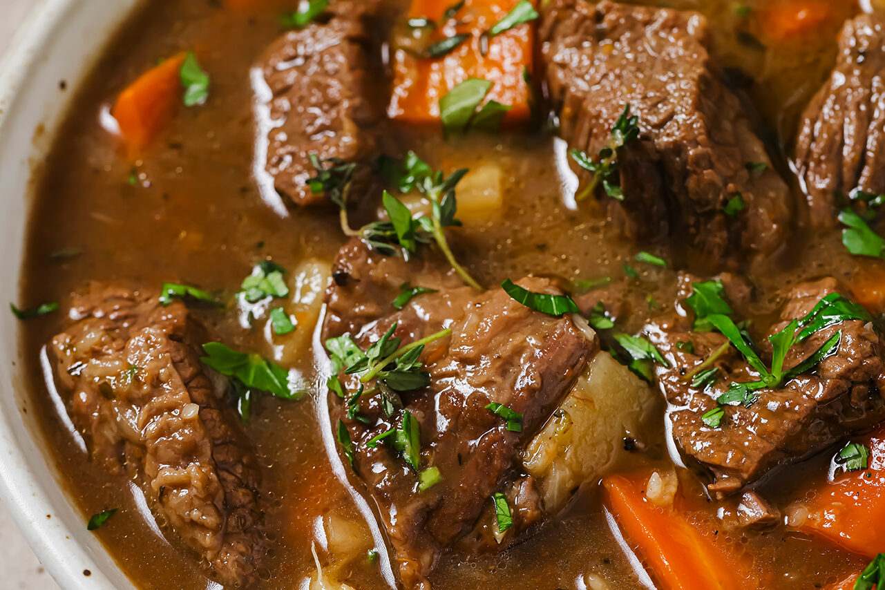 Dutch oven beef stew in a bowl topped with parsley.