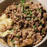 Ground beef and gravy served over mashed potatoes in a bowl.