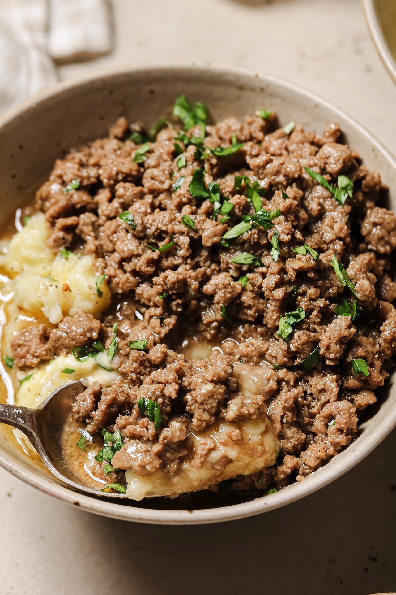 Ground beef and gravy served over mashed potatoes in a bowl.
