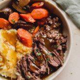 pot roast with gravy with a side of veggies and sweet potato.
