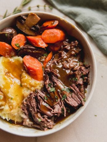 pot roast with gravy with a side of veggies and sweet potato.