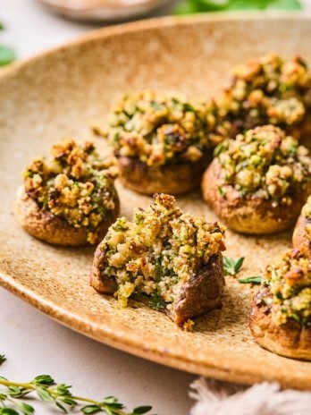 Stuffed mushrooms on a platter with a bite taken out of one.