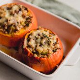 Two roasted stuffed pumpkins in a baking dish.