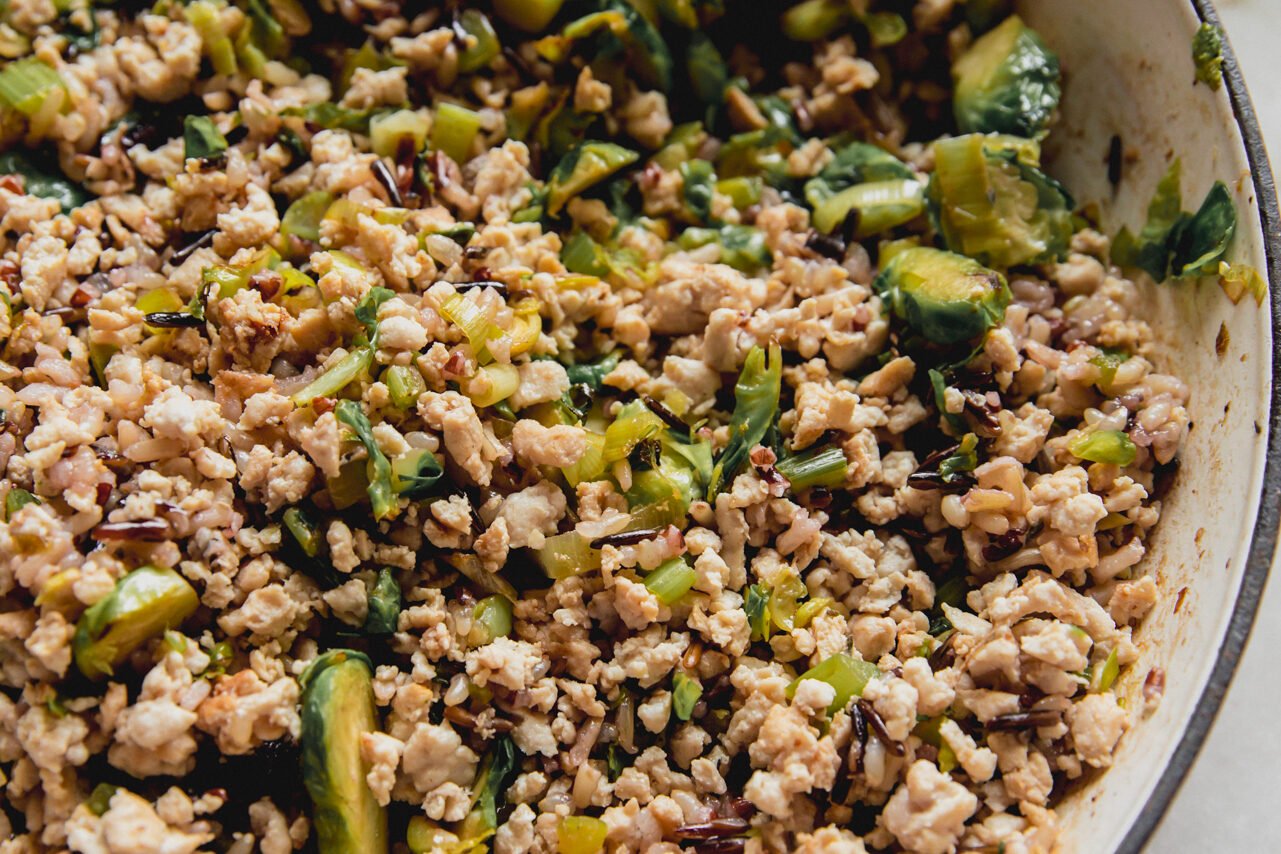 Cooked ground turkey, shredded brussels, wild rice and dried cranberries in a pan.