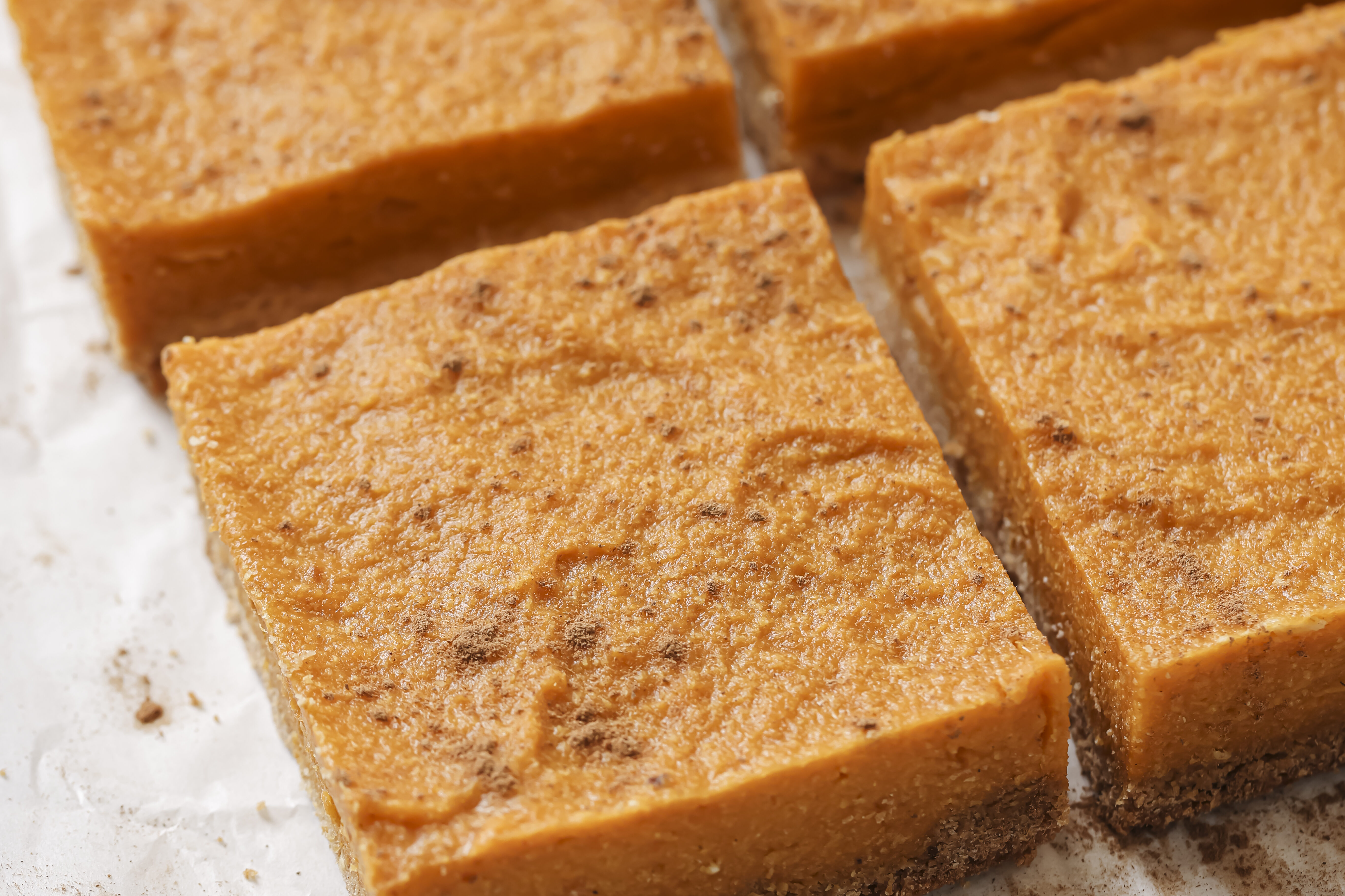 Pumpkin pie bars fully baked through and sliced, topped with cinnamon.
