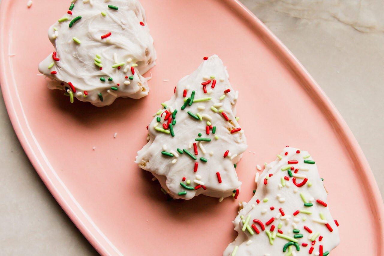 Three christmas tree cakes on a pink plate.