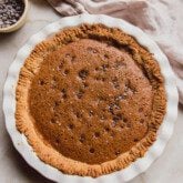 Chocolate chip cookie pie in a large white pan pan with a bowl of chocolate chips on the side.