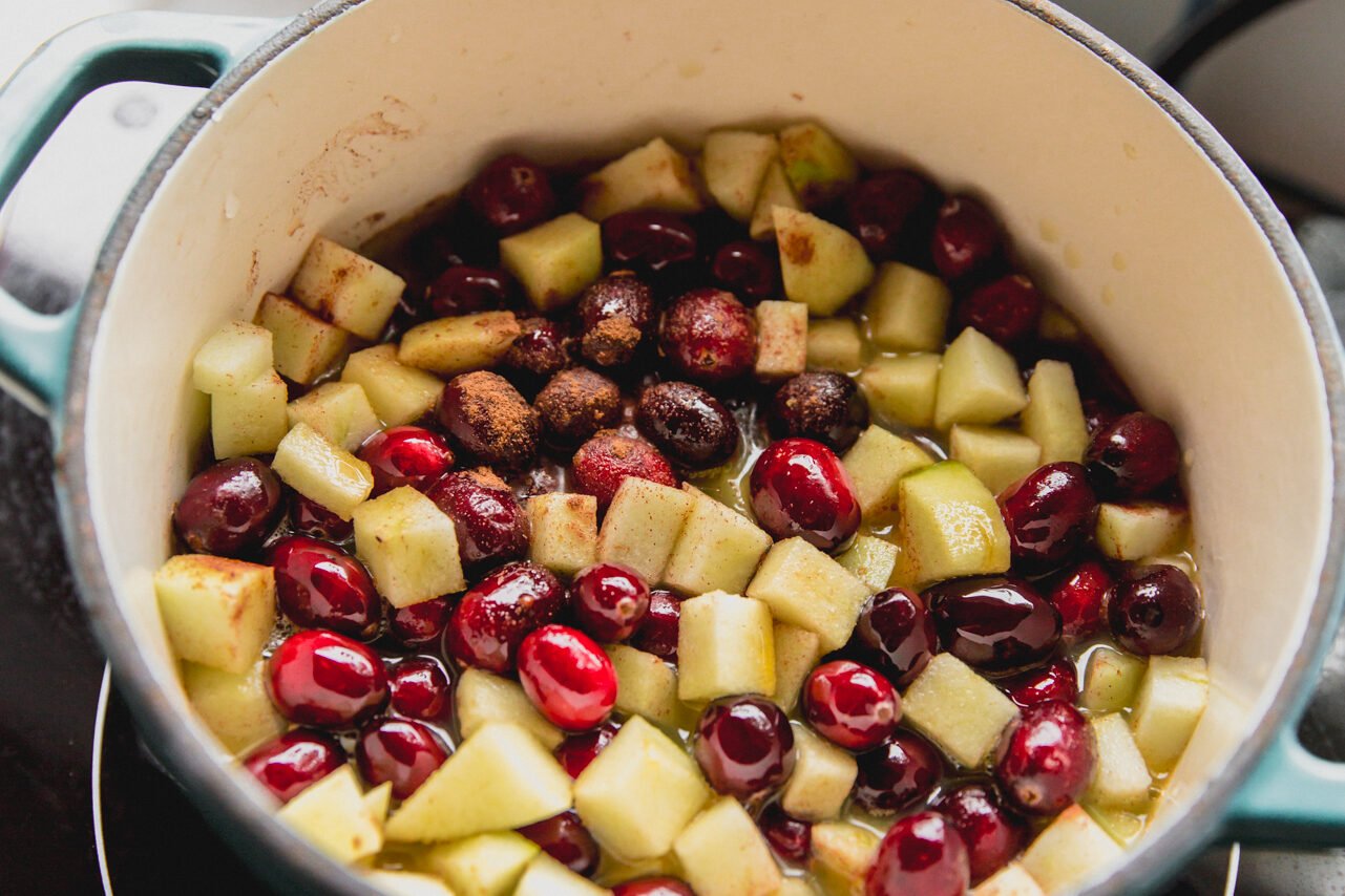 Apple cranberry sauce ingredients in a blue pot, ready to simmer.