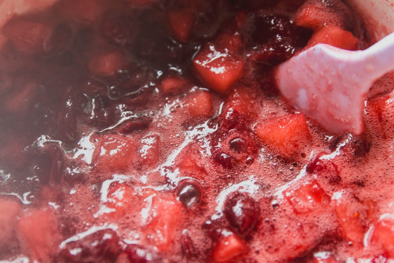 Apple cranberry sauce simmering in a pot.