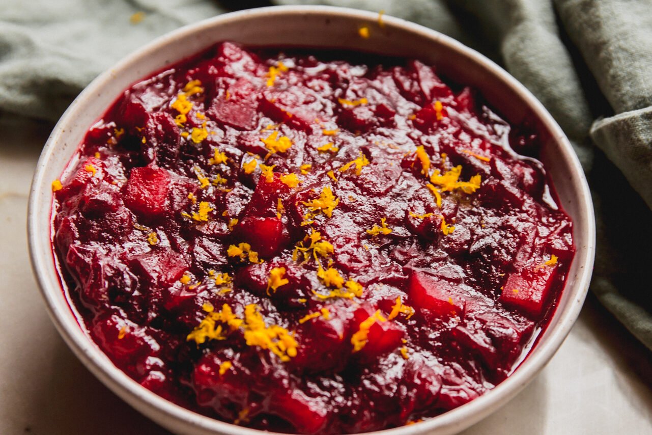Apple cranberry sauce topped with orange zest in a white bowl.