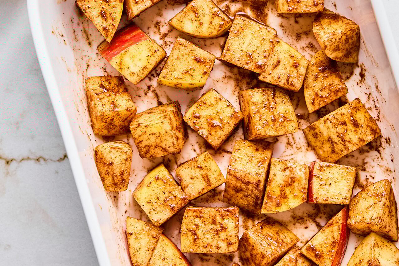 The diced apples in a baking sheet before anything is added to them.