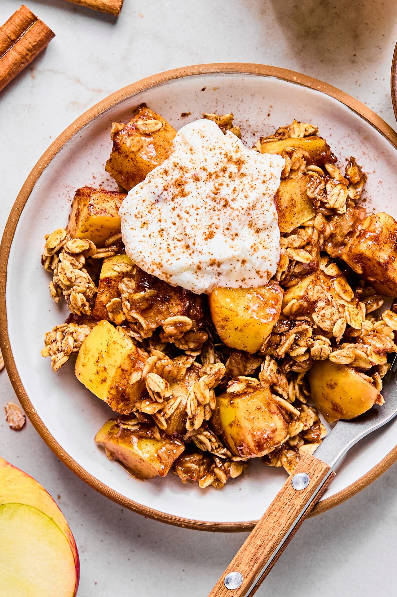 A bowl with protein apple crisp in it topped with yogurt and cinnamon.