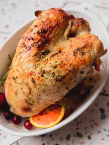Fully cooked slow cooker turkey breast in a white serving dish.