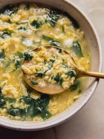 Stracciatella soup in a bowl with a large spoon.