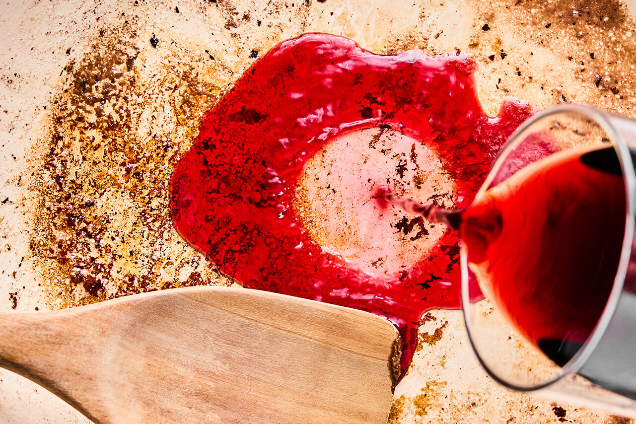 Wine being poured over a skillet to deglaze the pan.
