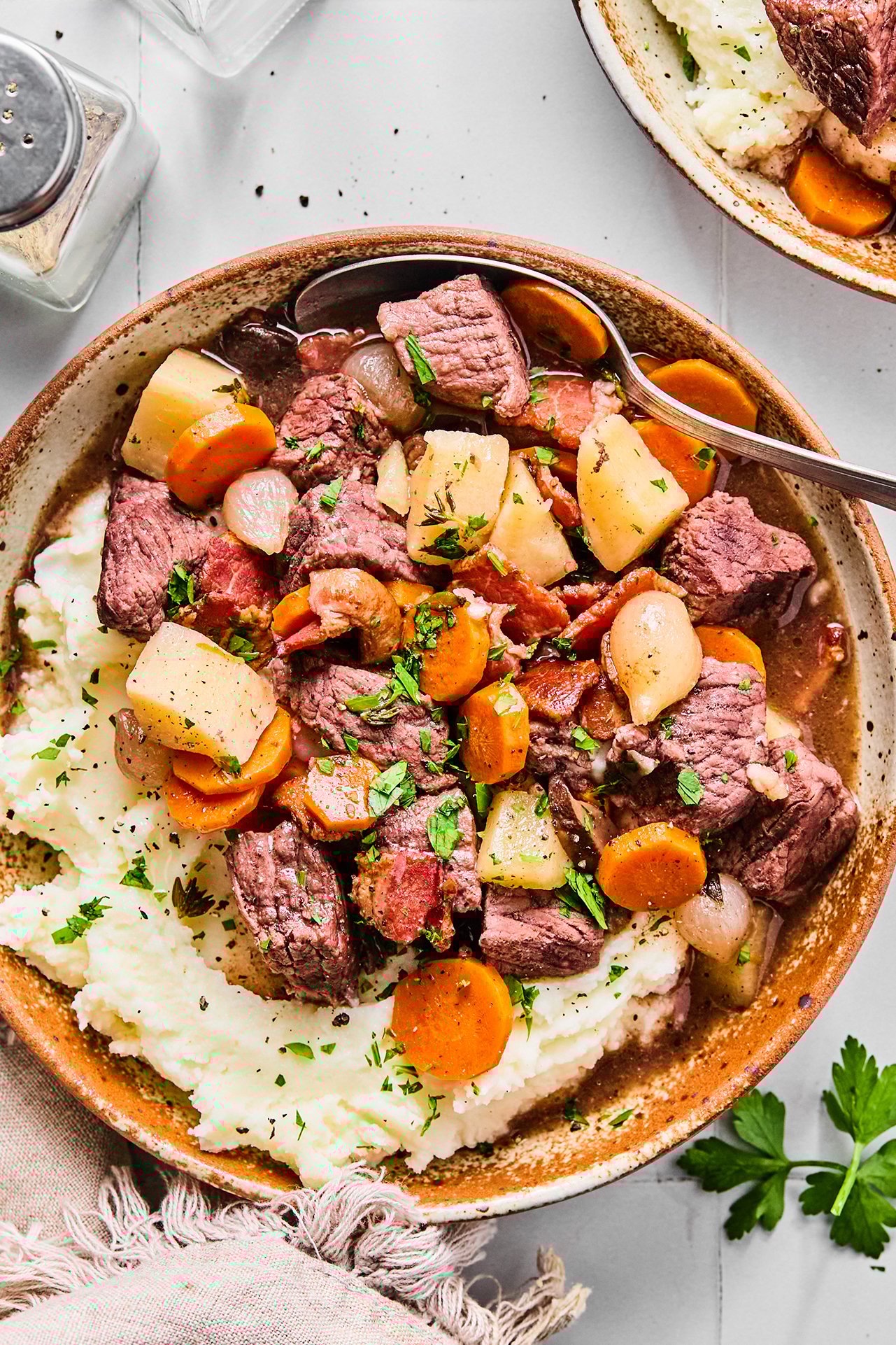 A bowl filled with potatoes topped with slow cooker beef bourguignon.