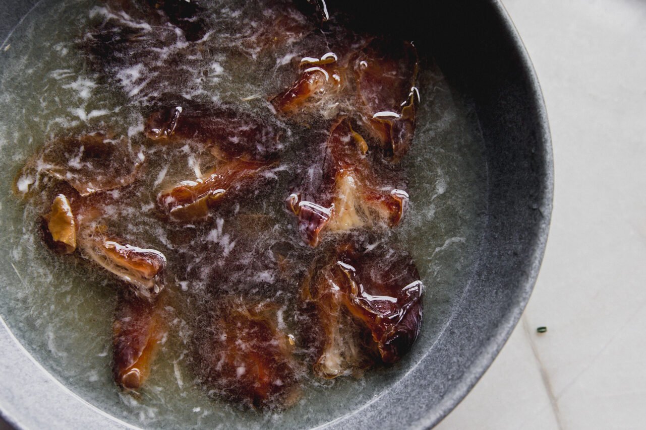 A grey bowl filled with dates soaking in hot water.