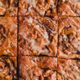 Gluten free cinnamon roll cake sliced into 9 slices and topped with a glaze icing.