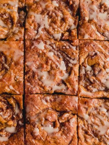 Gluten free cinnamon roll cake sliced into 9 slices and topped with a glaze icing.