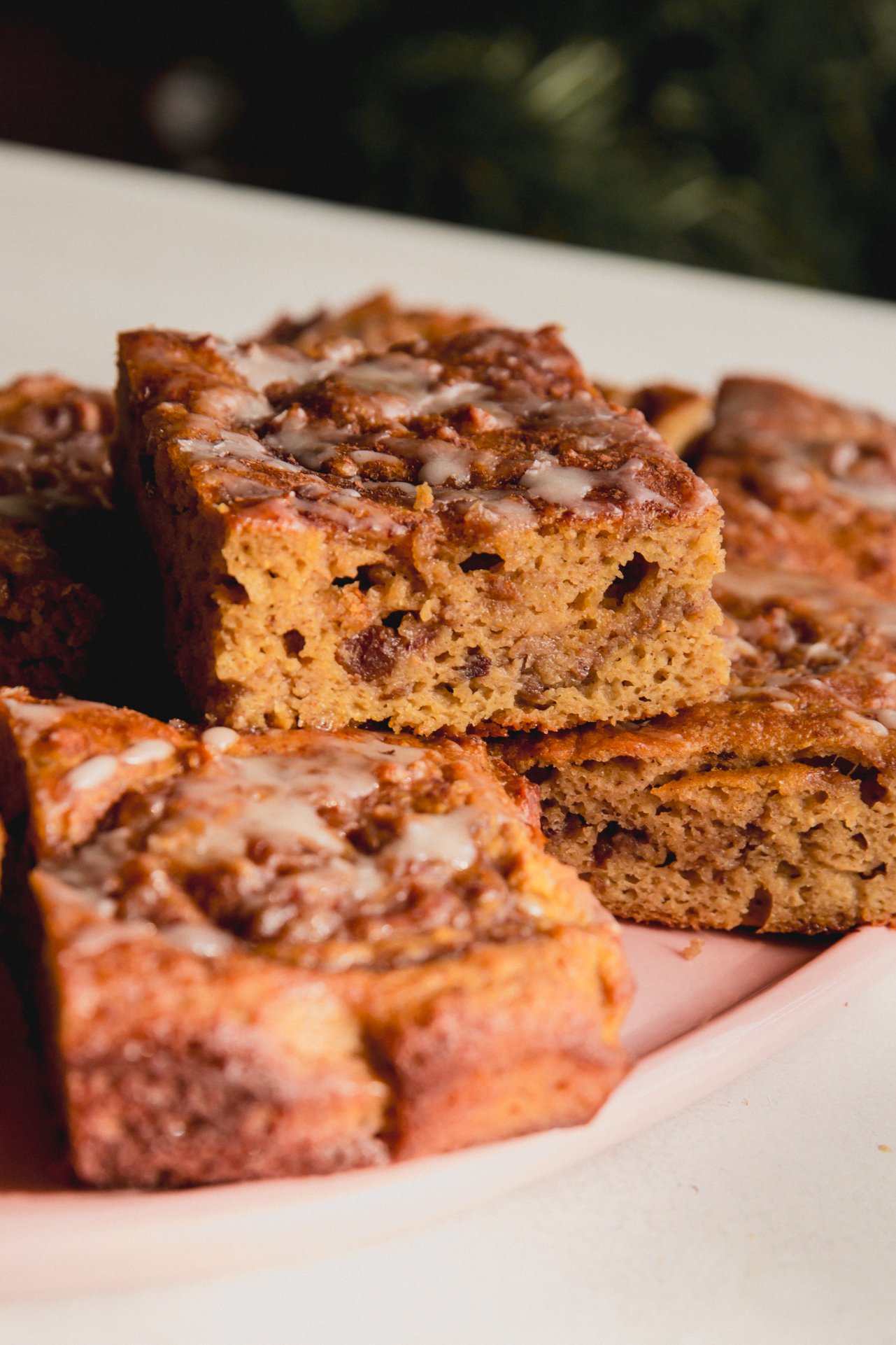 Pieces of cinnamon roll cake stacked on top of each other on a pink plate.