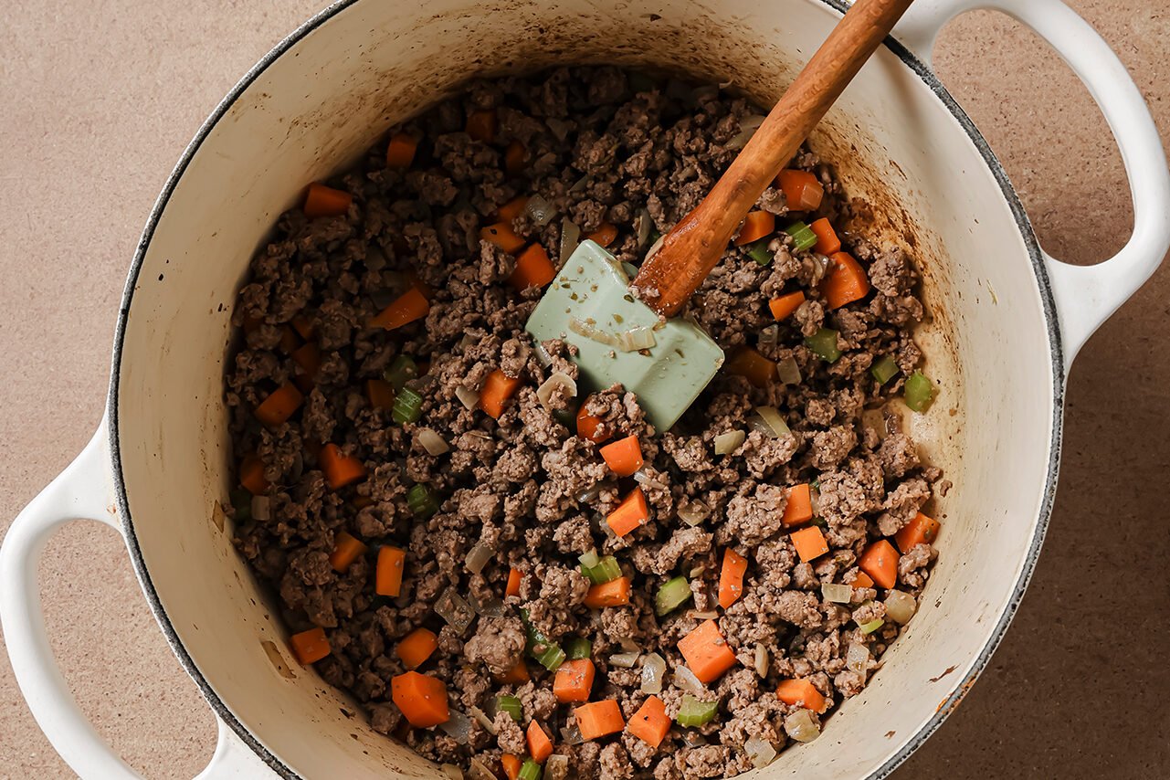 Ground beef and veggies cooking in a large dutch oven.