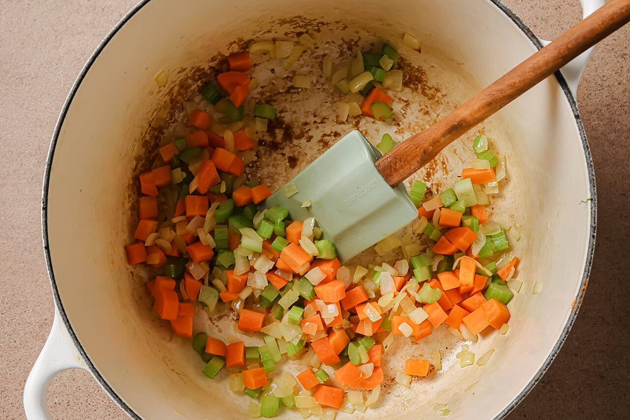 Onion, celery and diced onion cooking in a white dutch oven