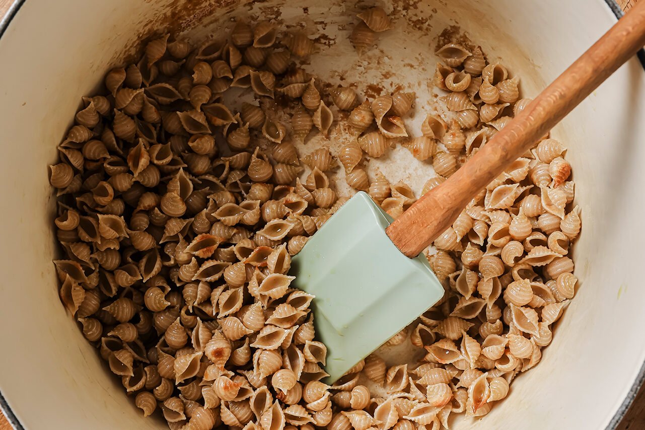 Pasta shells being toasted in a large dutch oven pot.