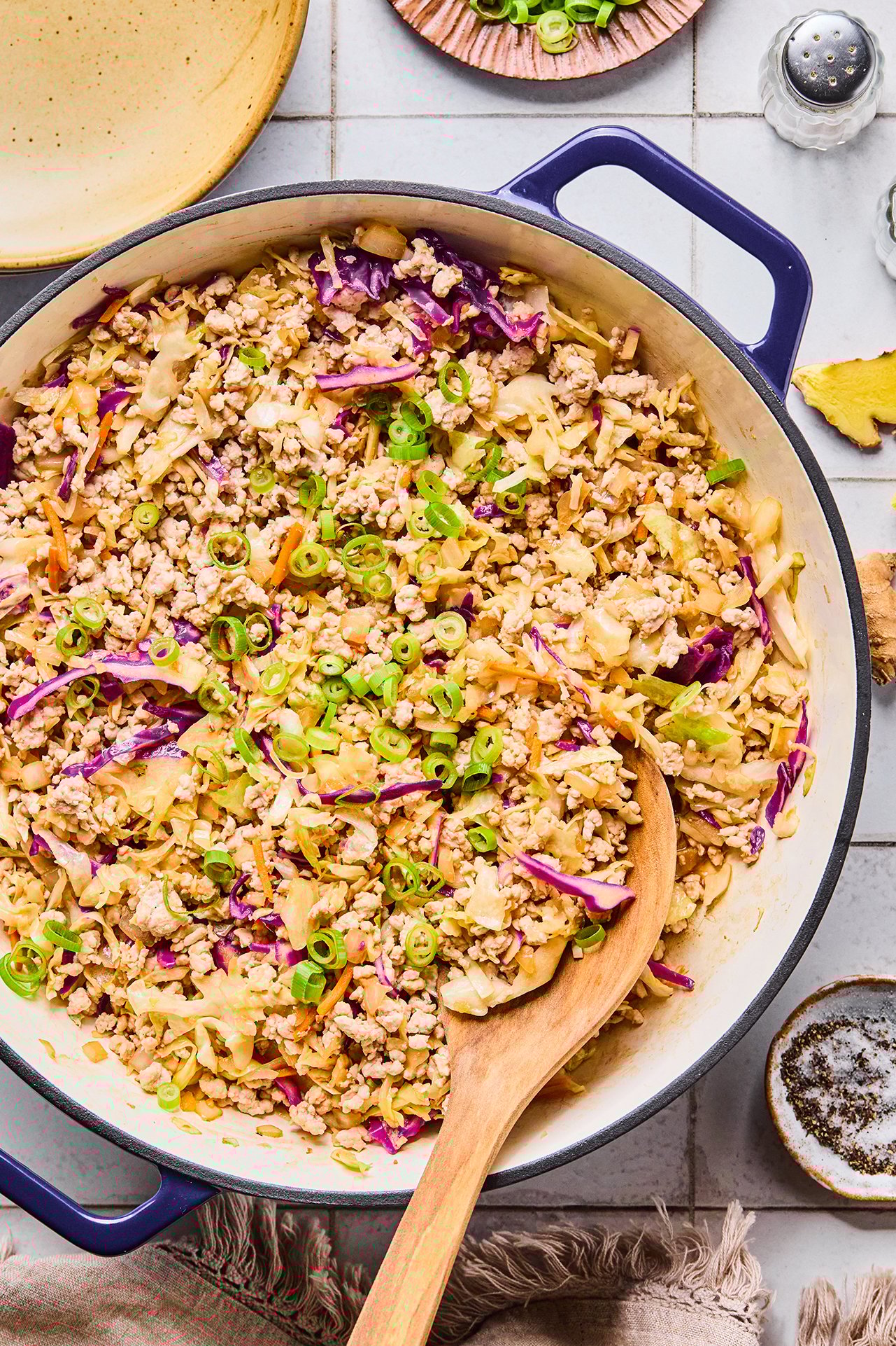 A Dutch oven filled with egg roll in a bowl after being cooked with a wooden serving spoon in it.