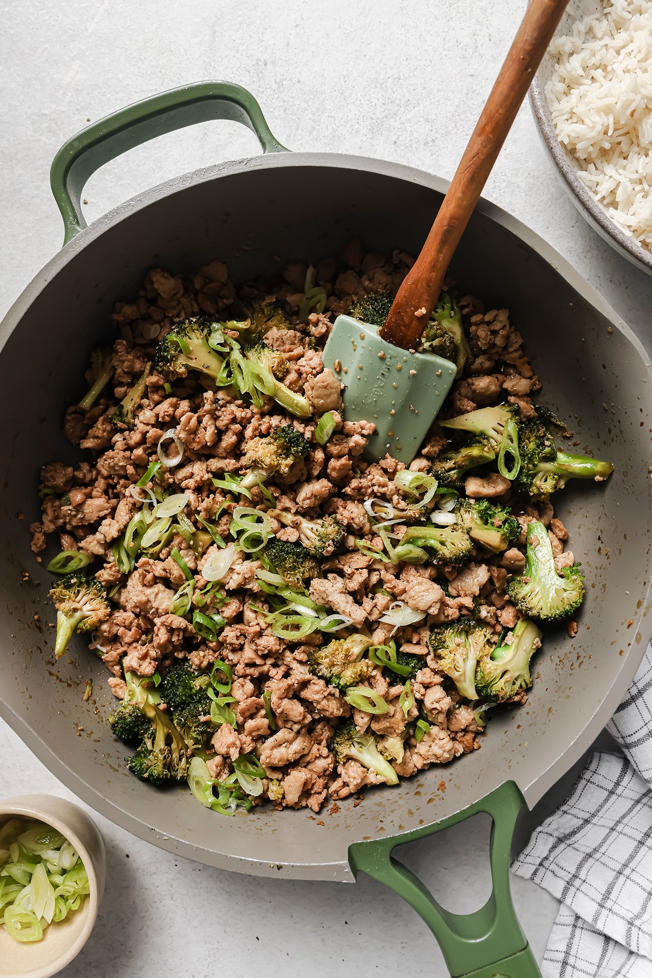 Ground chicken and broccoli fully cooked in a large green pan.