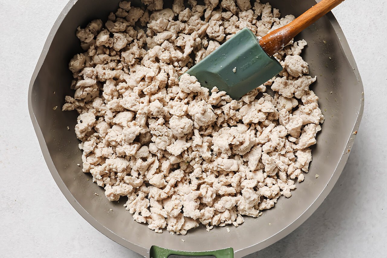 Ground chicken cooked, fully cooked and crumbled in a pan.