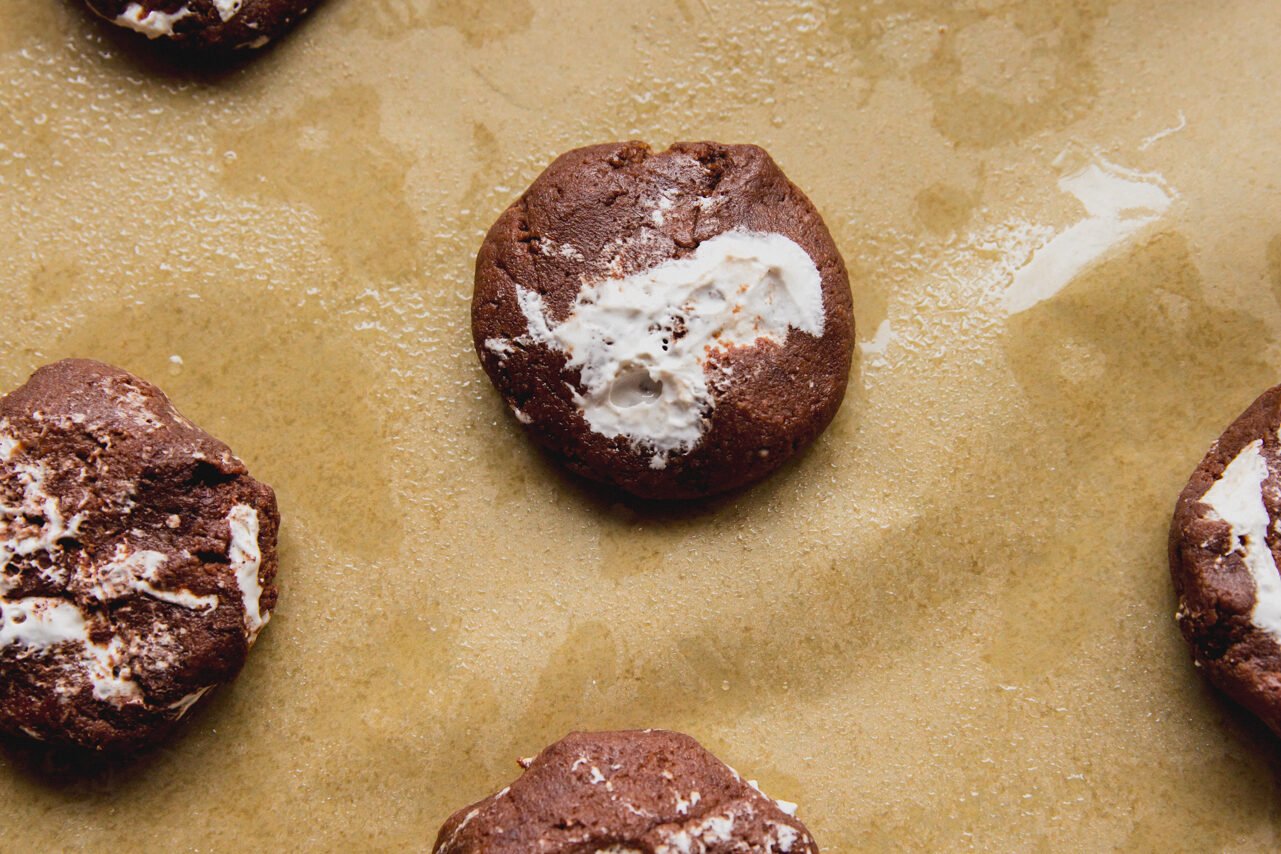 A piece of parchment paper topped with 6 cookies after baking in the oven.