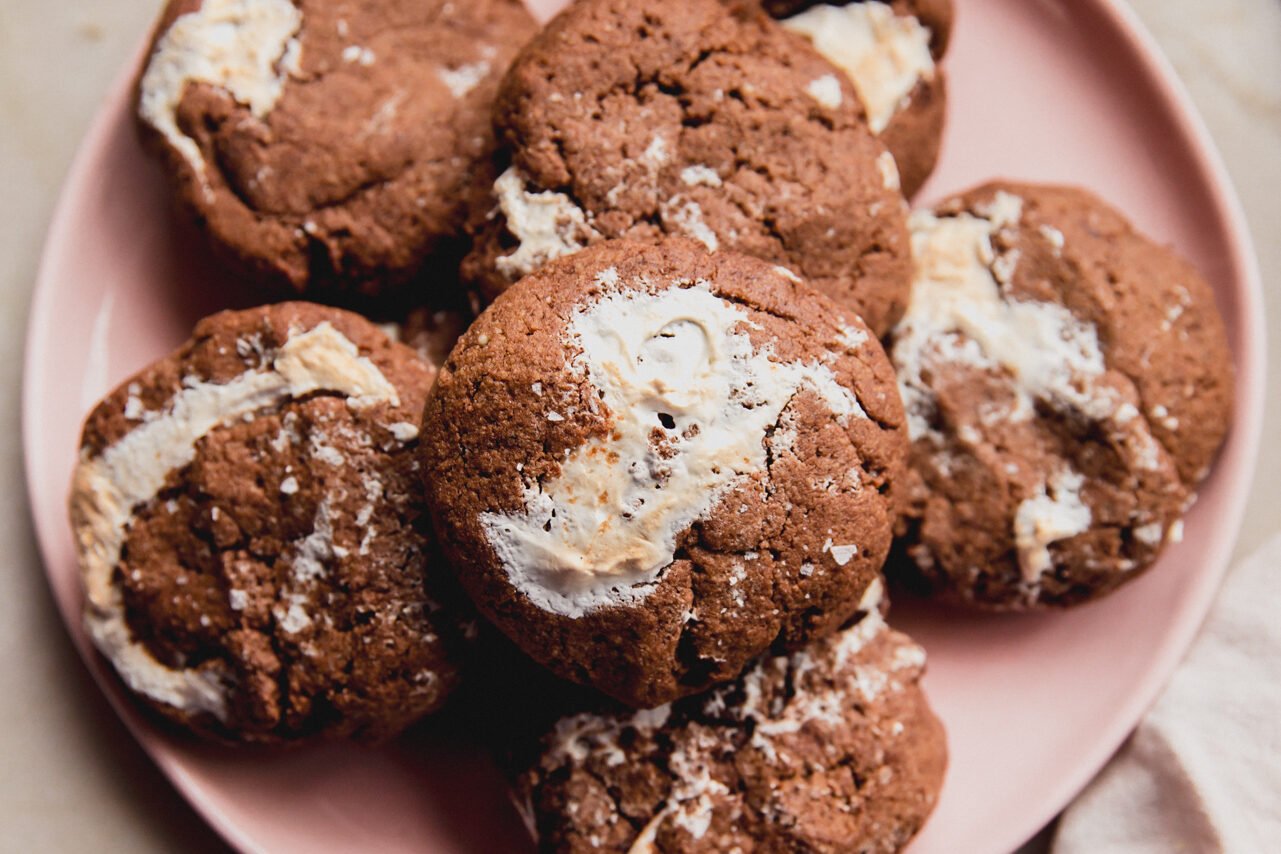A pink plate topped with a stack of chocolate marshmallow fluff cookies ready to be enjoyed.