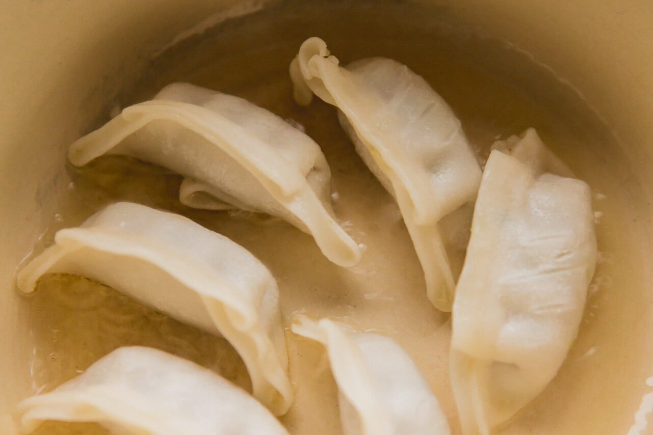 Potstickers in a pan before browning.