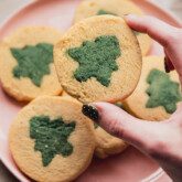 A pink plate of slice and bake cookies with a green christmas tree design.