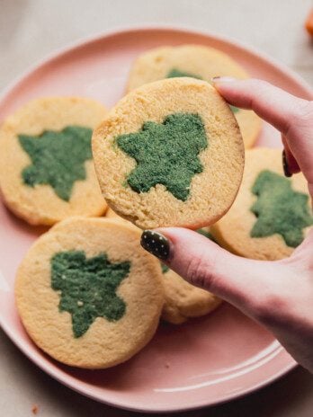 A pink plate of slice and bake cookies with a green christmas tree design.