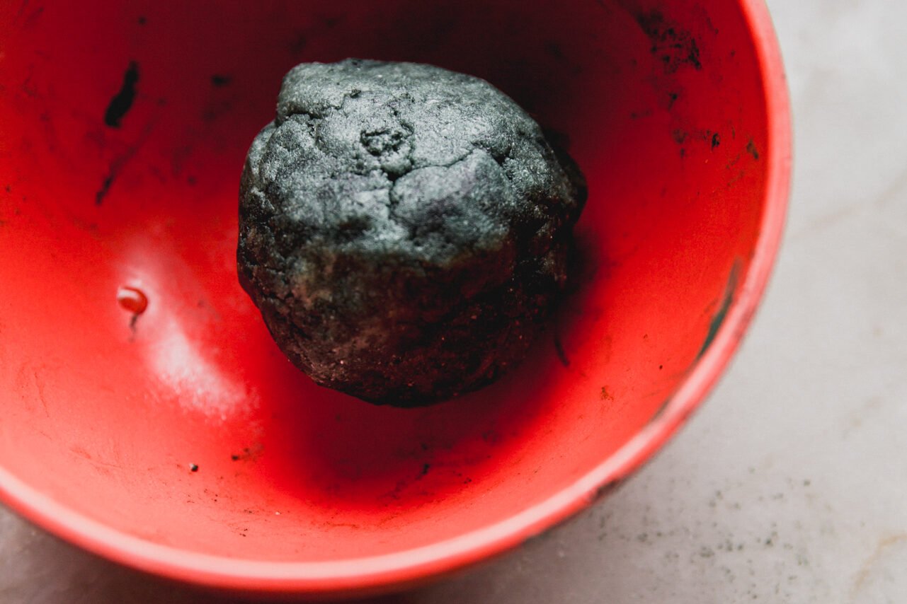 A red bowl with a ball of green dough in it.