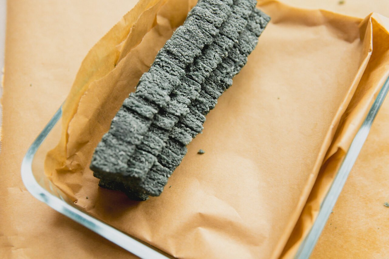 A glass container with parchment paper lining the bottom and a stack of green Christmas tree cut outs.