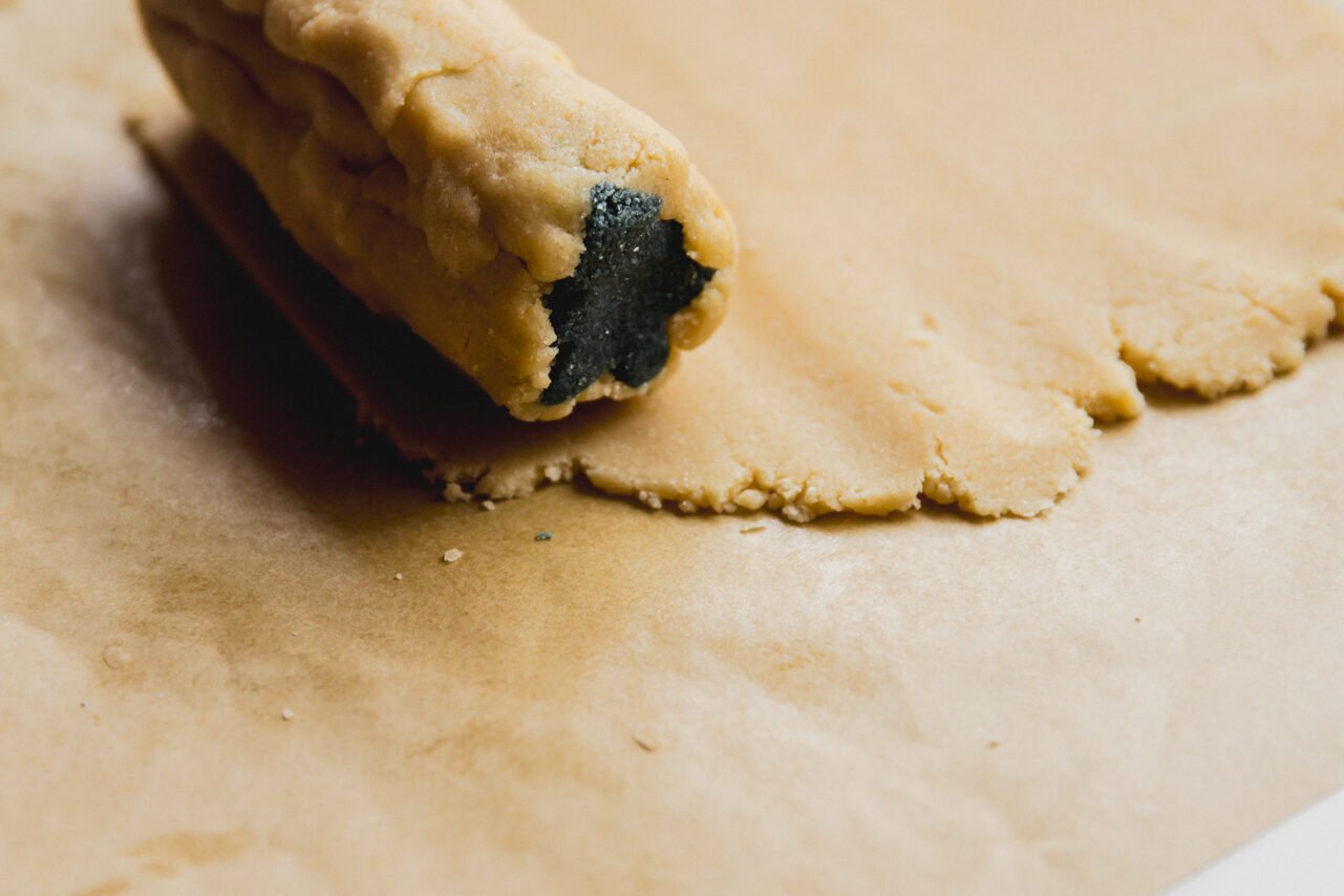 Uncolored dough being wrapped around the Christmas tree cutouts to incase the green dough in uncolored dough.