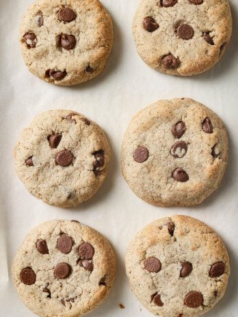 AIP chocolate chip cookies fully baked on a baking sheet with white parchment paper.