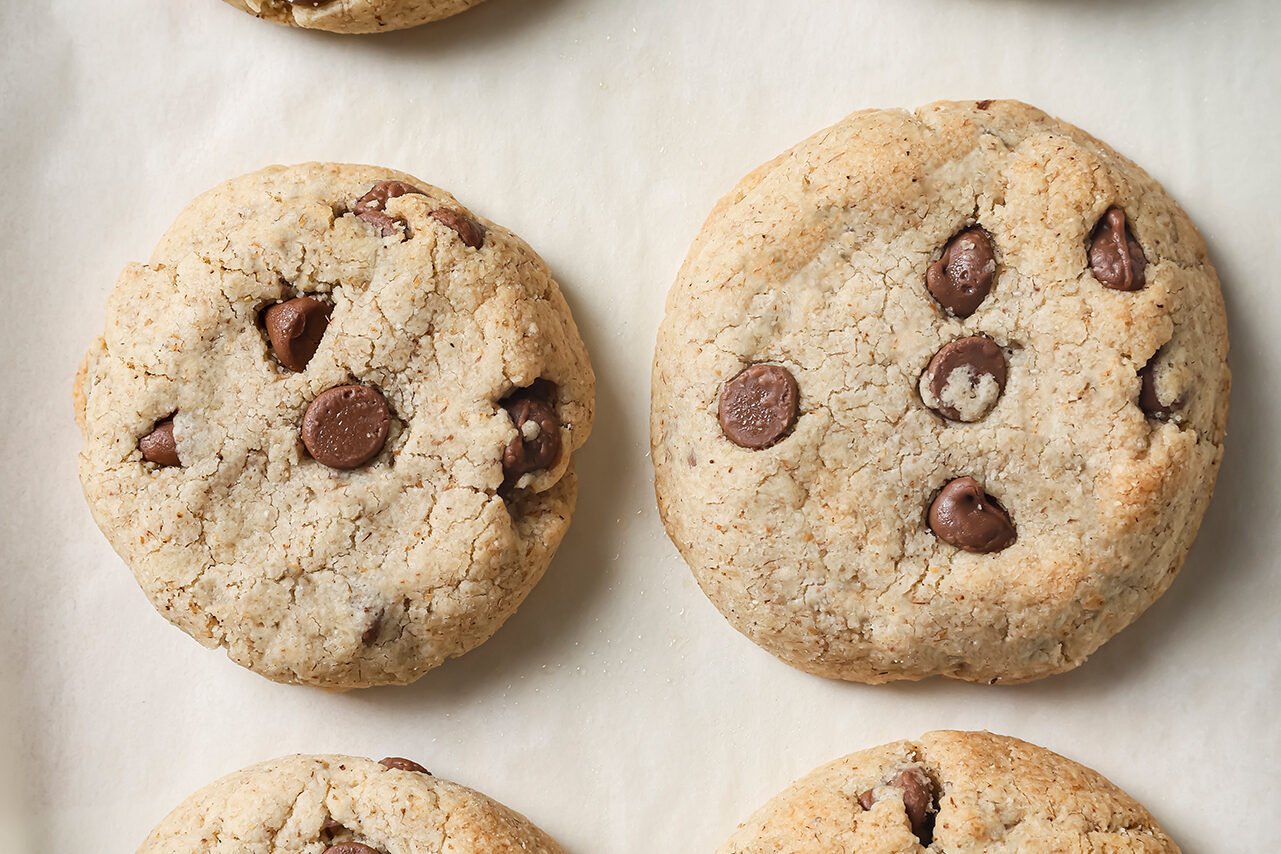 AIP chocolate chip cookies fully baked on a baking sheet with white parchment paper.