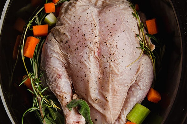 Whole chicken in a crock pot with veggies and herbs