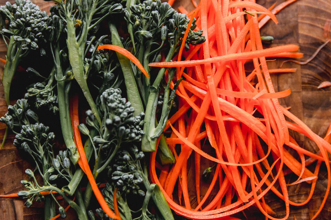 Broccoli and carrots cut up and on a cutting board before cooking.