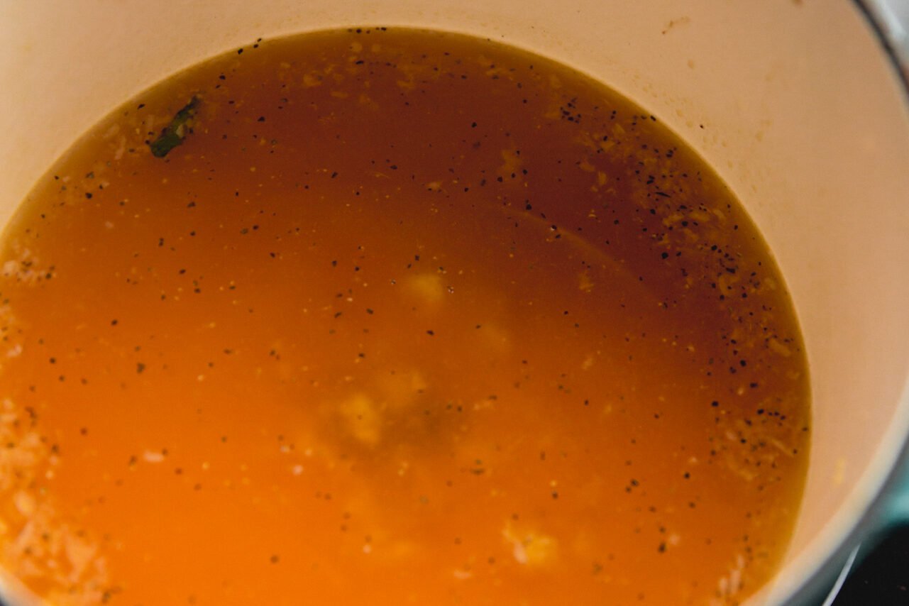 A Dutch oven with broth cooking in it.