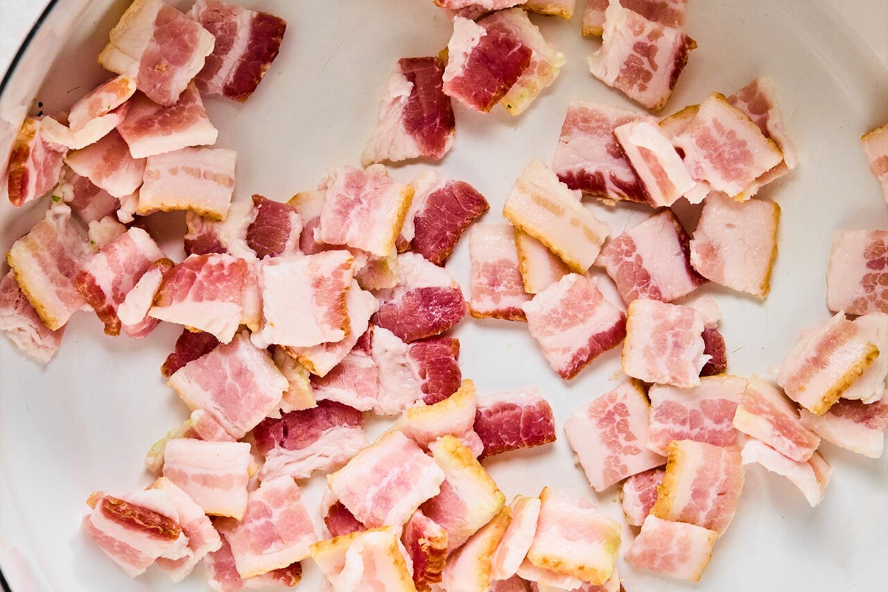 Bacon sauting in a pan on the stove.