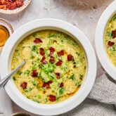 Breakfast egg drop soup in a bowl topped with bacon and green onion, with bacon on the side.