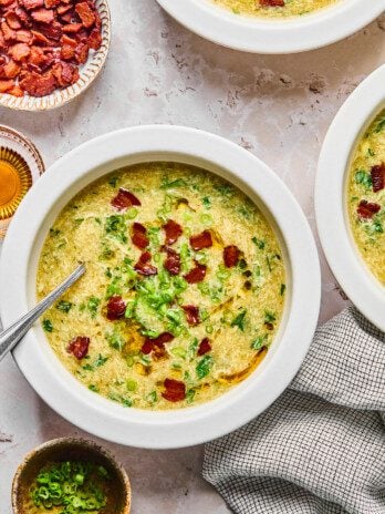 Breakfast egg drop soup in a bowl topped with bacon and green onion, with bacon on the side.
