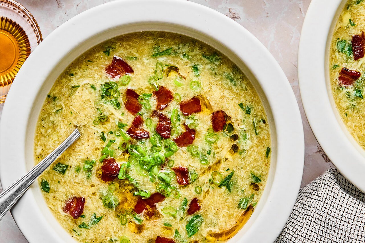 Breakfast egg drop soup in a bowl topped with bacon and green onion, with bacon on the side.