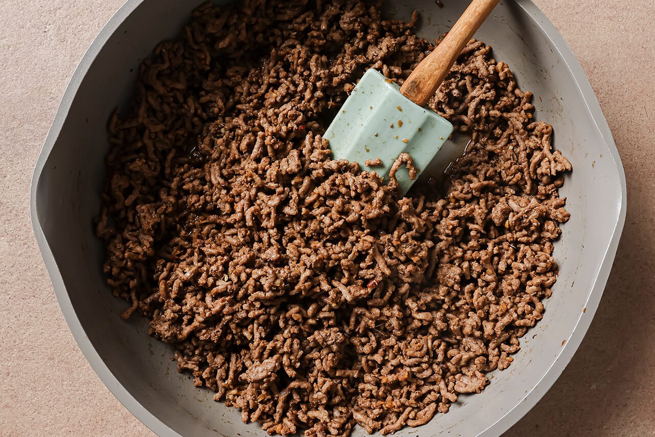 Ground beef in a pan after cooking and the sauce added.